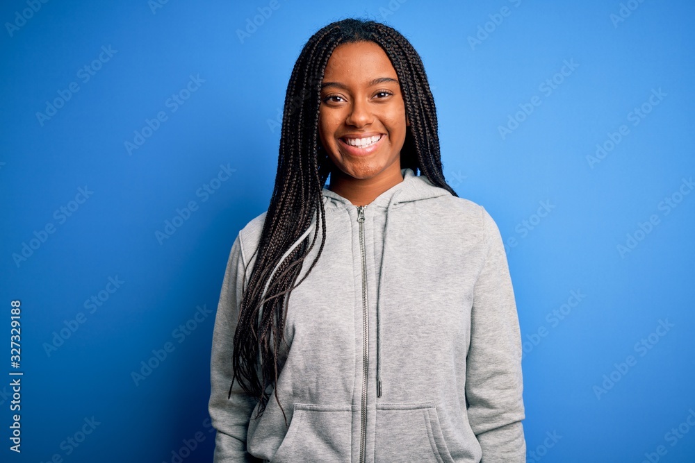Young african american athlete woman wearing sports sweatshirt over blue isolated background with serious expression on face. Simple and natural looking at the camera.
