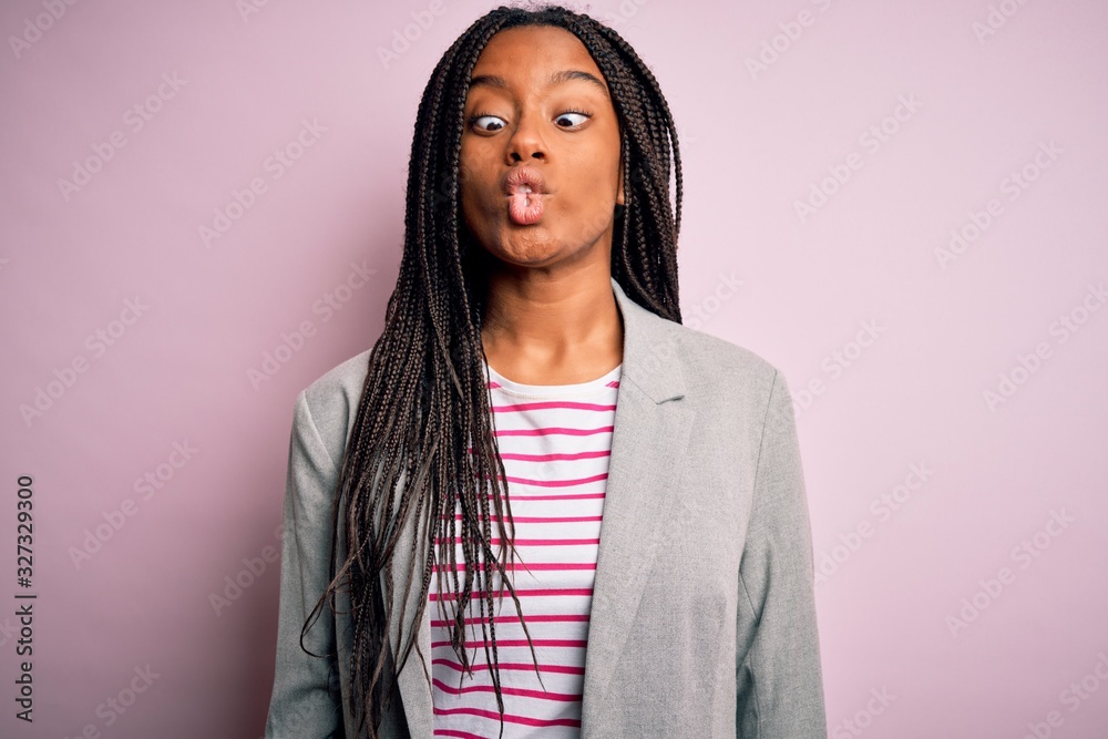 Young african american business woman standing over pink isolated background making fish face with lips, crazy and comical gesture. Funny expression. Young african american business woman standing over pink isolated background making fish face with lips, crazy and comical gesture. Funny expression.