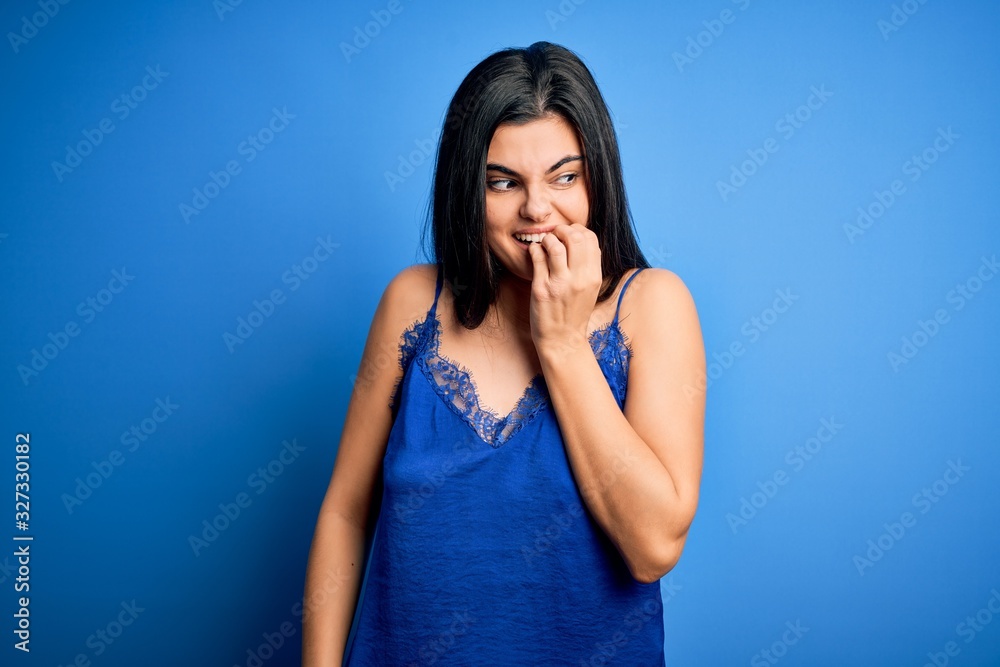 Young beautiful brunette woman wearing elegant and comfortable blue lingerie underwear looking stressed and nervous with hands on mouth biting nails. Anxiety problem. Young beautiful brunette woman wearing elegant and comfortable blue lingerie underwear looking stressed and nervous with hands on mouth biting nails. Anxiety problem.