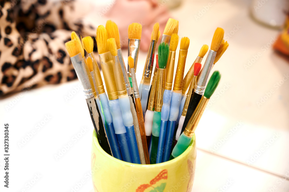 Ein Set von Malpinseln und gelben und grünen Borsten stehen kopfüber in einer Tasse und sind bereit für den Einsatz Ein Set von Malpinseln und gelben und grünen Borsten stehen kopfüber in einer Tasse und sind bereit für den Einsatz