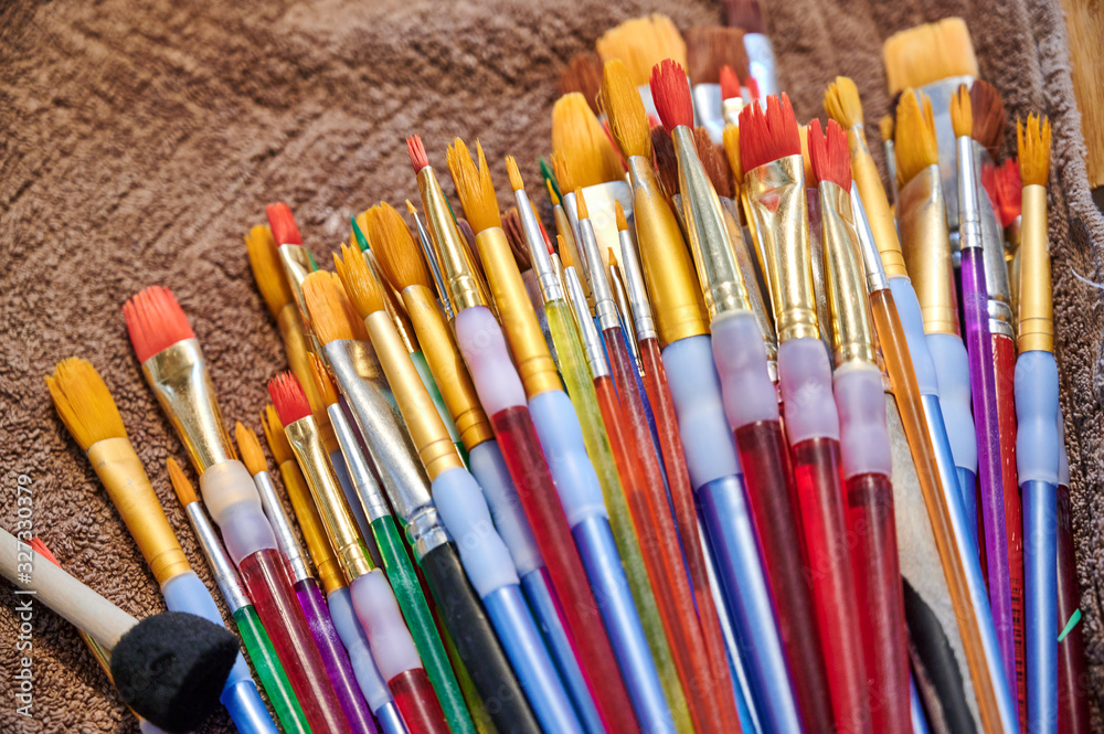 Bunte Pinsel mit gelben Borsten liegen auf einem brauen Handtuch und trocknen Bunte Pinsel mit gelben Borsten liegen auf einem brauen Handtuch und trocknen