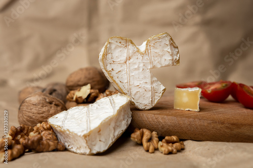 Neufchatel, French cheese made in Normandy from cow's milk. with walnut kernels and cherry tomatoes on a wooden wooden background. Copy space white mold growing