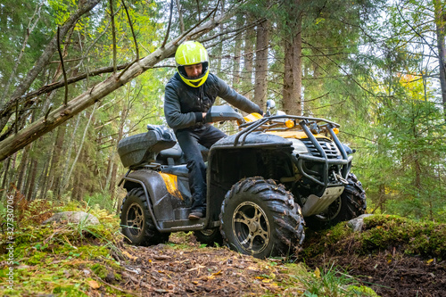 ATV. A man looks at the wheels of a Quad bike. Journey through the forest on a Quad bike. A man rides a Quad bike on the road. Off-road transport. The equipment of the driver of the ATV.