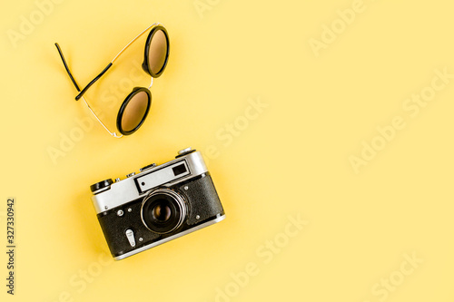 Traveler accessories concept on yellow background. Retro camera, model plane, airplane, sunglasses. Summer background. Flat lay, top view.