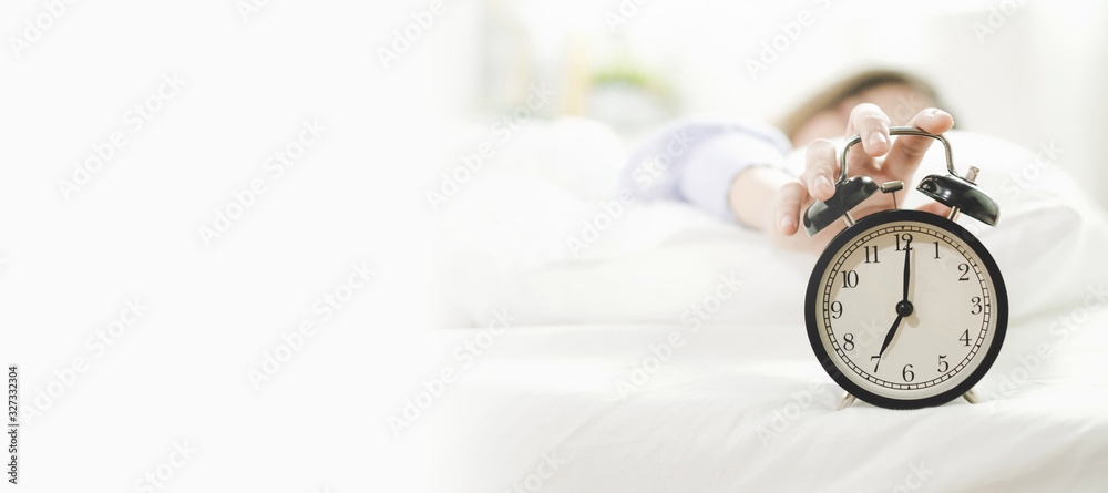 panoramic banner copy space. young asian woman sleeping on bed pressing snooze button on black vintage alarm clock at seven o'clock morning in bed room at home, good morning, healthy sleep and concept panoramic banner copy space. young asian woman sleeping on bed pressing snooze button on black vintage alarm clock at seven o'clock morning in bed room at home, good morning, healthy sleep and concept