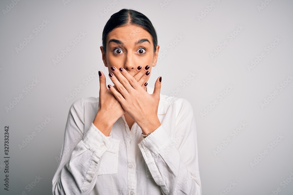 Young beautiful brunette woman wearing casual shirt over isolated white background shocked covering mouth with hands for mistake. Secret concept. Young beautiful brunette woman wearing casual shirt over isolated white background shocked covering mouth with hands for mistake. Secret concept.