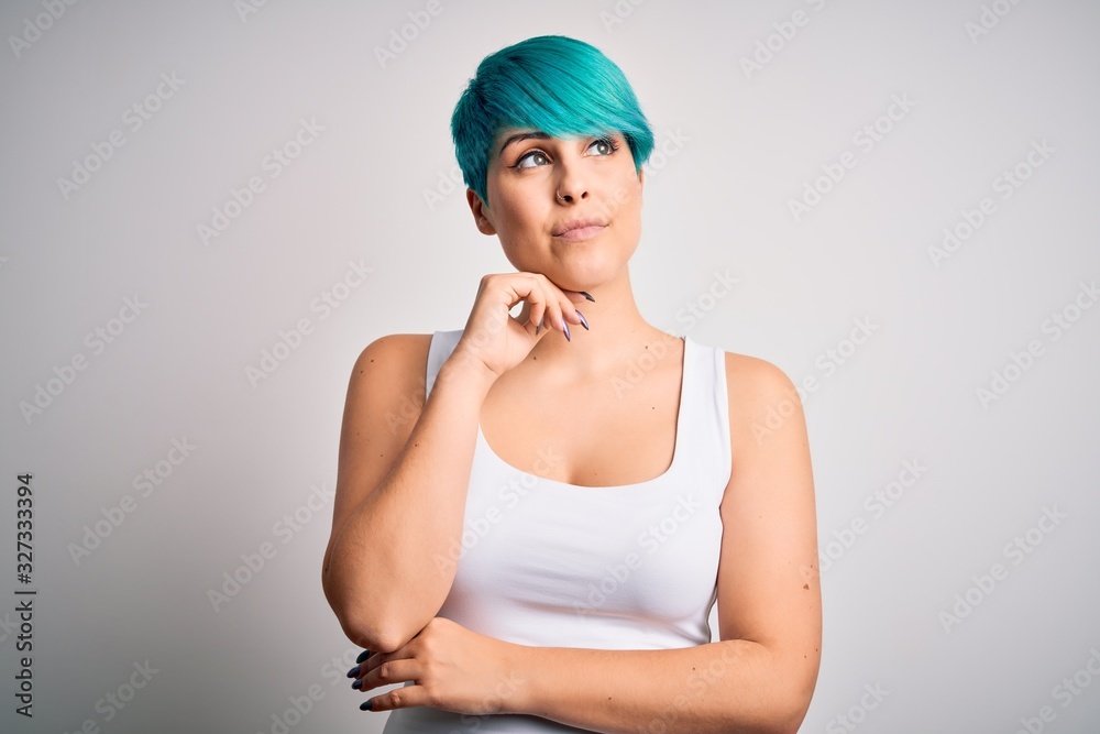 Young beautiful woman with blue fashion hair wearing casual t-shirt over white background with hand on chin thinking about question, pensive expression. Smiling and thoughtful face. Doubt concept. Young beautiful woman with blue fashion hair wearing casual t-shirt over white background with hand on chin thinking about question, pensive expression. Smiling and thoughtful face. Doubt concept.