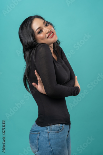 beautiful curvy asian woman with black top and blue jeans on turquoise background happy faces © Kencana Studio
