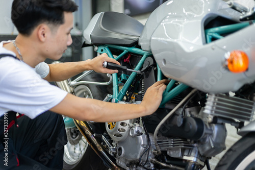 Asian mechanic man fixing the retro motorcycle in the garage