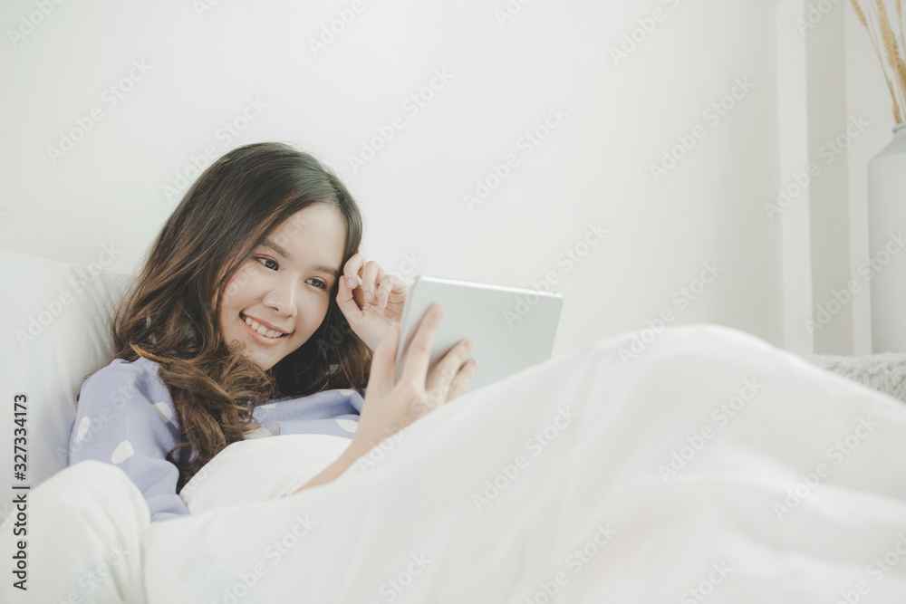 happy young asian pretty woman smiling watching online movie stream with digital mobile tablet and lying on bed at home in morning, video call connection, social network and technology concept happy young asian pretty woman smiling watching online movie stream with digital mobile tablet and lying on bed at home in morning, video call connection, social network and technology concept