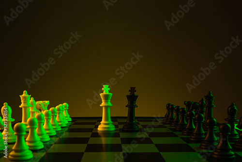 Chess pieces on a chessboard, game, Confrontation of kings. Yellow green neon color. The concept of confrontation, career, competition, startup.