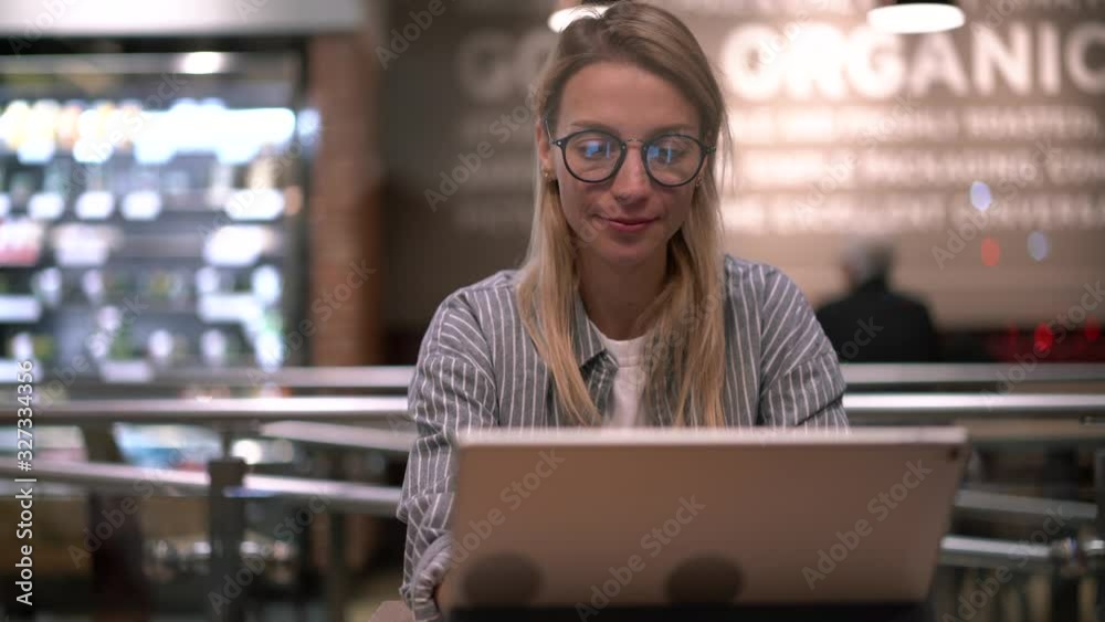 Successful hipster girl in glasses using cellphone and digital tablet during remote work in coffee shop drinking tasty caffeine beverage and networking, concept of millennial generation Z