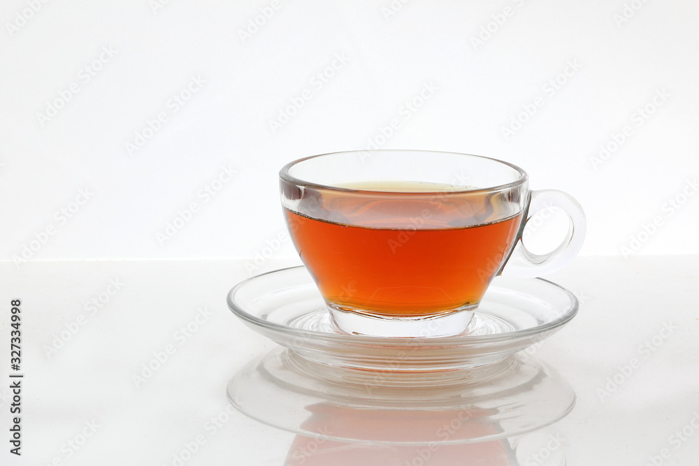 Clear licker tea in a transparent glass cup saucer spoon on white background