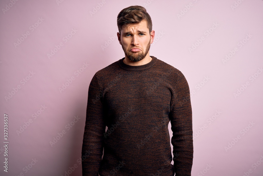 Young blond man with beard and blue eyes wearing casual sweater over pink background depressed and worry for distress, crying angry and afraid. Sad expression. Young blond man with beard and blue eyes wearing casual sweater over pink background depressed and worry for distress, crying angry and afraid. Sad expression.