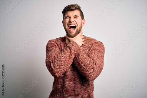 Young blond man with beard and blue eyes wearing casual sweater over white background shouting suffocate because painful strangle. Health problem. Asphyxiate and suicide concept.