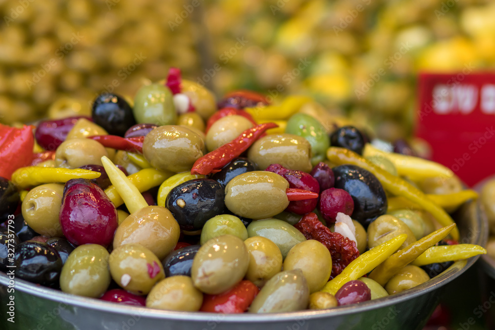 A pile of pickled olives from different varieties. Mix with hot peppers, in a metal bowl. Blurred background. Arabic style. The Old Market, Jerusalem. A pile of pickled olives from different varieties. Mix with hot peppers, in a metal bowl. Blurred background. Arabic style. The Old Market, Jerusalem.