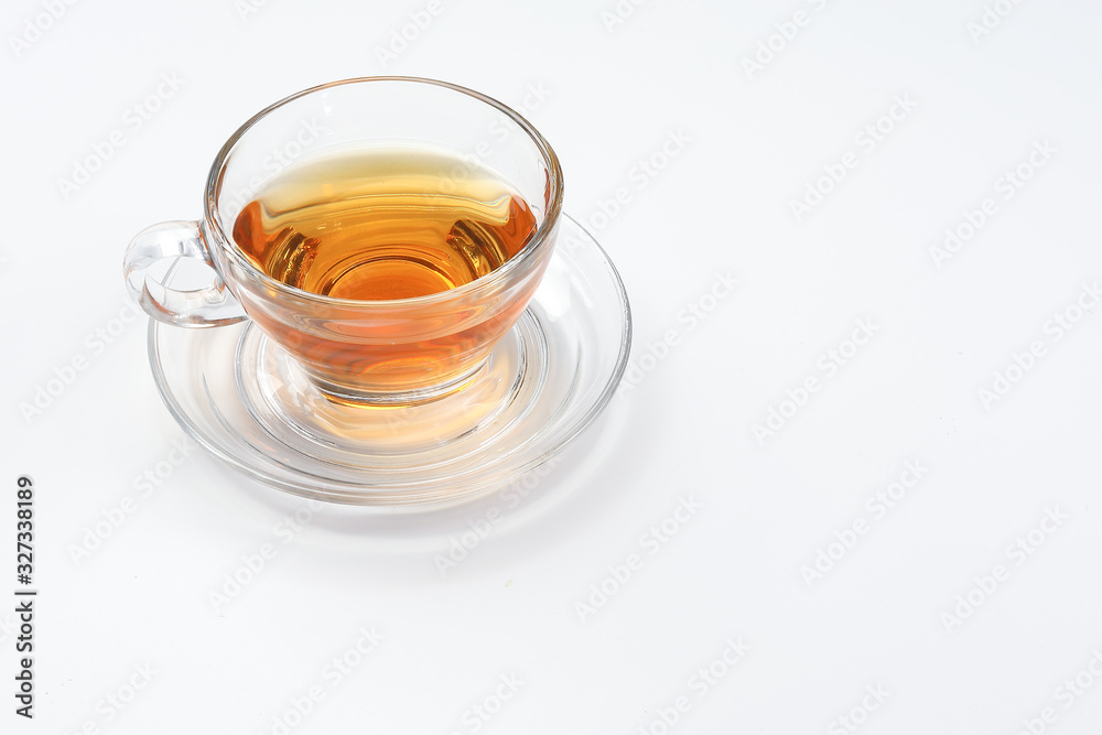 Clear licker tea in a transparent glass cup saucer spoon on white background Clear licker tea in a transparent glass cup saucer spoon on white background