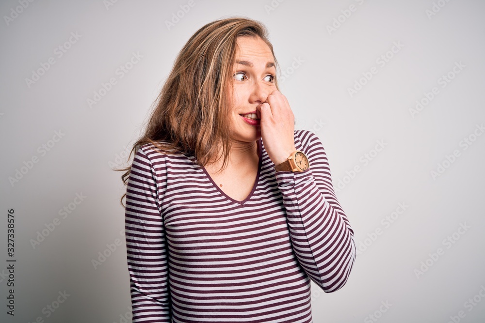 Young beautiful blonde woman wearing casual striped t-shirt over isolated white background looking stressed and nervous with hands on mouth biting nails. Anxiety problem. Young beautiful blonde woman wearing casual striped t-shirt over isolated white background looking stressed and nervous with hands on mouth biting nails. Anxiety problem.