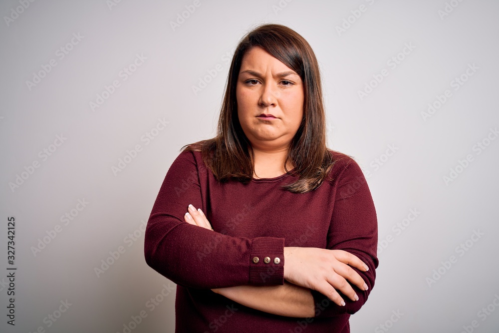 Fototapeta premium Beautiful brunette plus size woman wearing casual sweater over isolated white background skeptic and nervous, disapproving expression on face with crossed arms. Negative person.