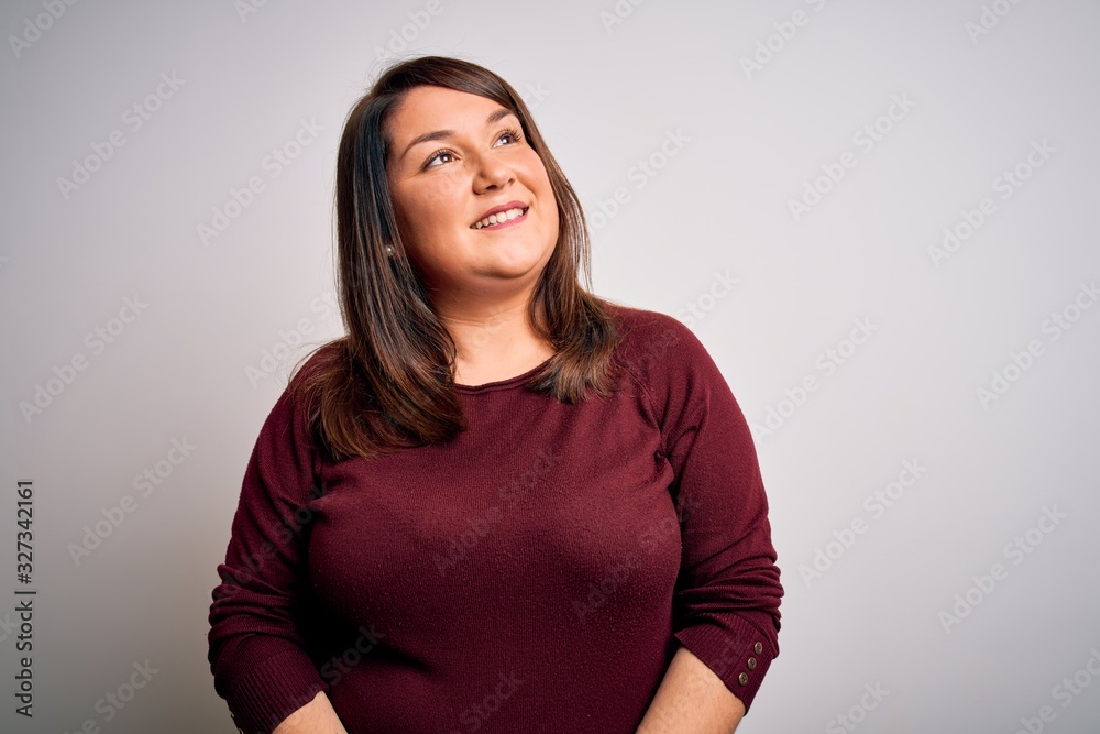 Obraz premium Beautiful brunette plus size woman wearing casual sweater over isolated white background looking away to side with smile on face, natural expression. Laughing confident.