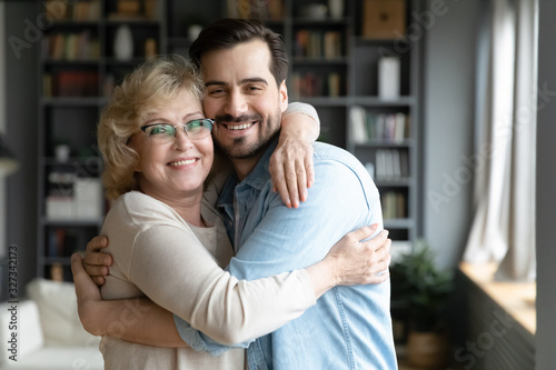 Portrait of happy senior mom and grownup son cuddling