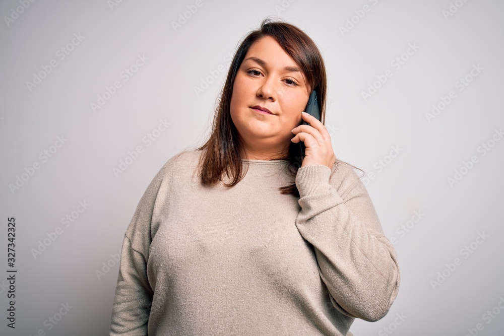 Beautiful plus size woman having a conversation talking on smartphone over isolated background with a confident expression on smart face thinking serious Beautiful plus size woman having a conversation talking on smartphone over isolated background with a confident expression on smart face thinking serious