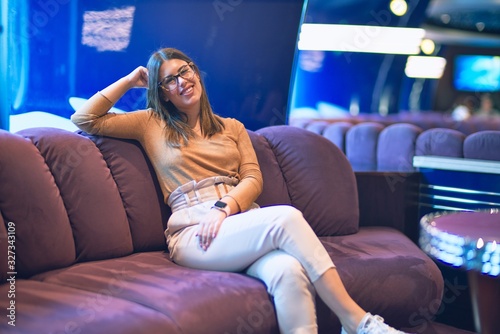 Young beautiful woman smiling happy and confident. Sitting on the sofa with smile on face at bar