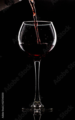 Silhouette of a glass on a black background  a red drink is poured on top