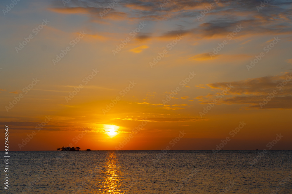 orange tropical sunset with little island on horizon line orange tropical sunset with little island on horizon line