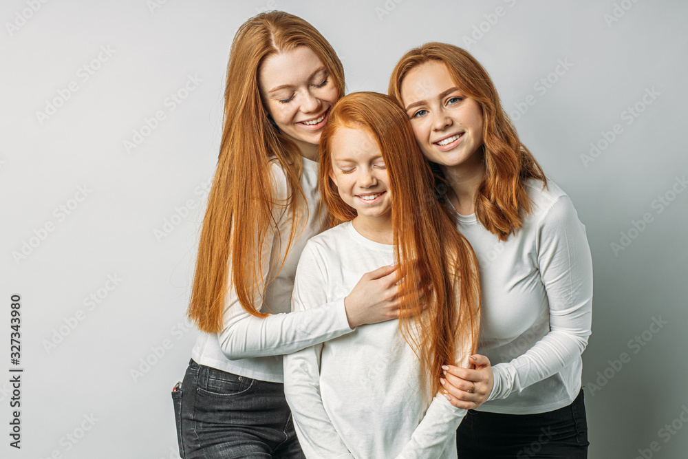portrait of three red haired people gathered in studio, posing and looking at camera together, wearing white clothes. natural beauty, naturalness concept. rare type of people portrait of three red haired people gathered in studio, posing and looking at camera together, wearing white clothes. natural beauty, naturalness concept. rare type of people