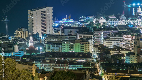 Cityscape of Monte Carlo, Monaco night timelapse with roofs of buildings and traffic on roads.