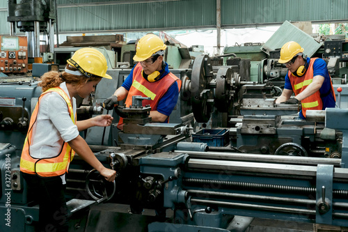 Engineer with Female mechanical worker with yellow safety helmet checking on production in a factory. Industrial, Mechanic, Engineering Concept. Motion blur.
