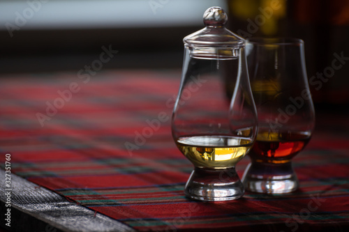 Special tulip-shaped glass for tasting of Scotch whisky on distillery in Scotland, UK and red tartan