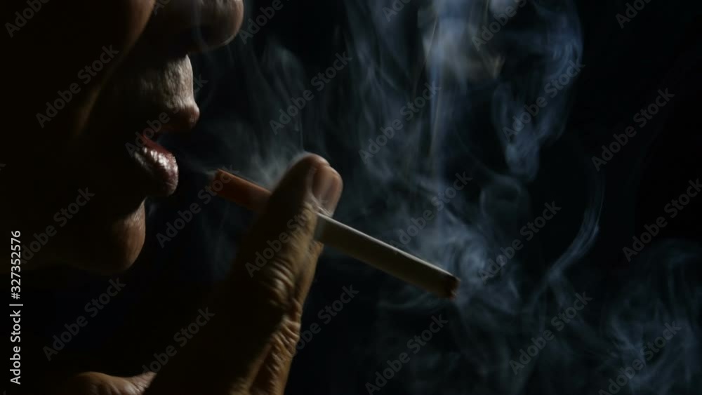 Footage of man smoking a cigarette on black background .