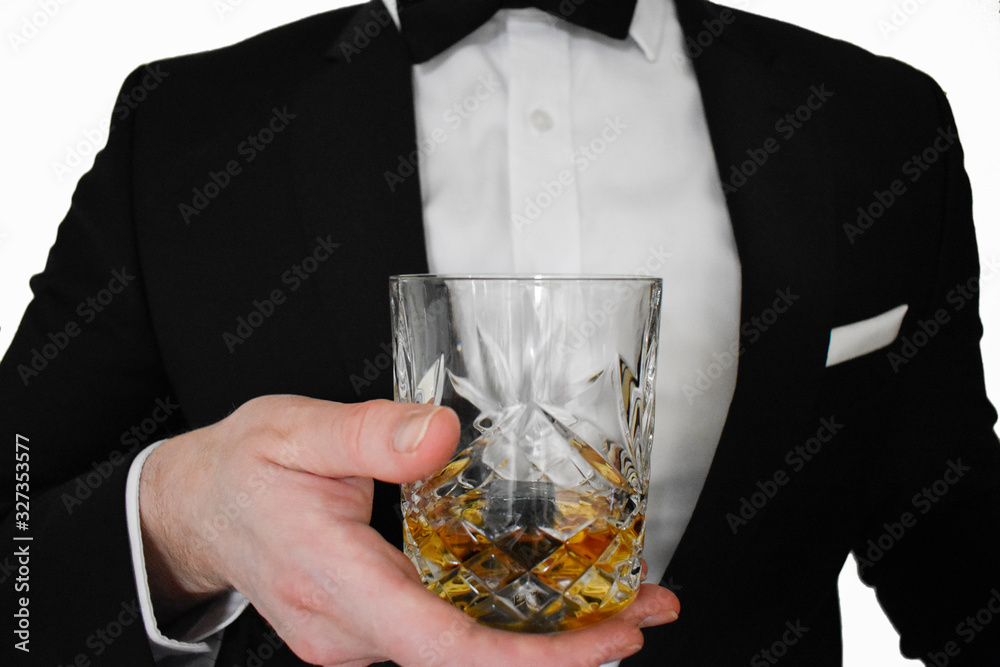Φωτογραφία A close up view of a man in a black tuxedo offering a glass of whiskey