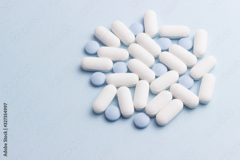 White and blue pills against blue background