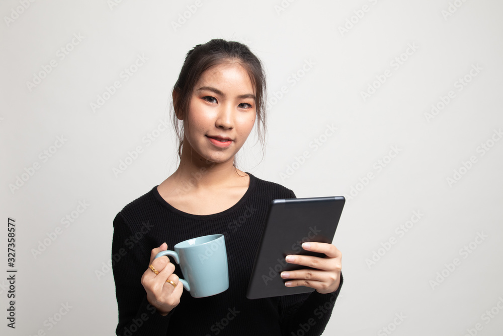 Young Asian woman with a computer tablet and coffee. Young Asian woman with a computer tablet and coffee.