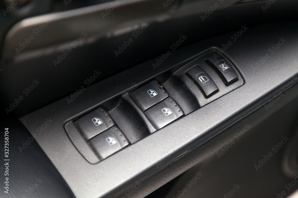 The control buttons for opening and closing windows of doors and electric controls on the door in gray with upholstery in a luxury modern car.