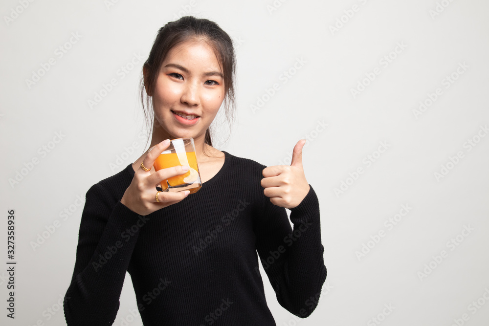 Young Asian woman thumbs up drink orange juice. Young Asian woman thumbs up drink orange juice.