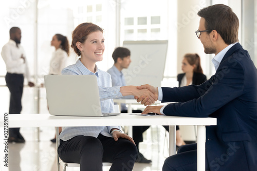 Smiling attractive woman handshaking with businessman for success conversation. © fizkes