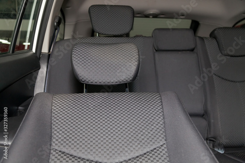 Upholstery of the seats of the passenger compartment with headrest of a luxury car with black fabric material in a workshop for hauling vehicles with a seam of thread.