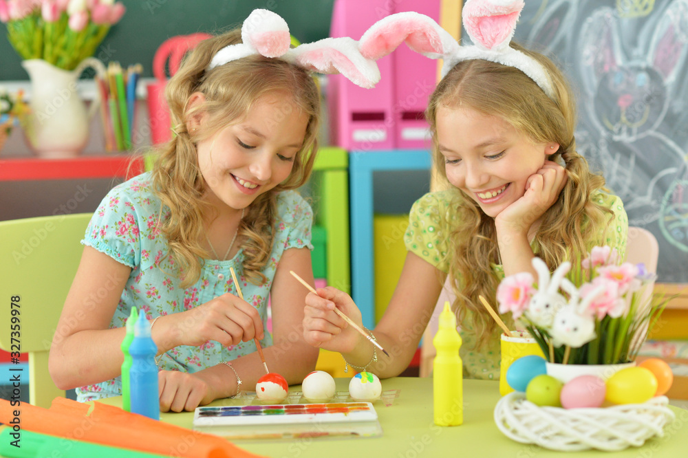 Girls wearing rabbit ears decorating Easter eggs at home Girls wearing rabbit ears decorating Easter eggs at home