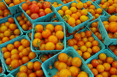 Yellow cherry tomatoes in light blue baskets closeup farmer market view