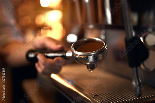 man's hand holds a portafilter with ground coffee.close up side view photo, secret of making perfect coffee photo