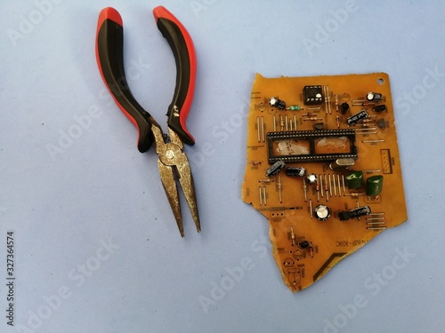 old circuit board with radio components broken by pliers on a light blue background