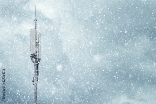 Tower with a cellular antenna for mobile phones against the sky in winter in snowy weather