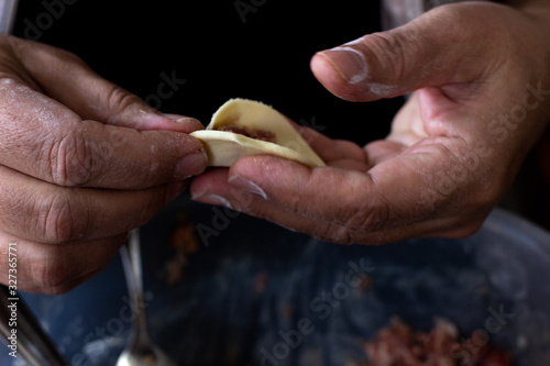 Homemade meat dumplings. Sculpt dumplings. Dumplings with minced meat sculpts cook in the kitchen. Prepare homemade dumplings on the table, sprinkled with flour. to cook dumplings with meat