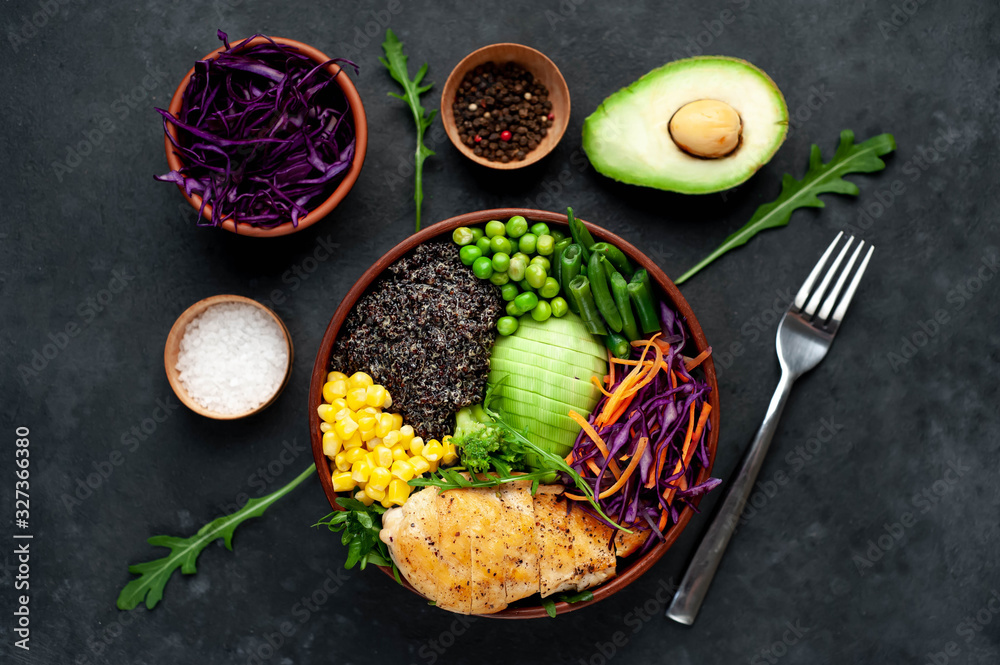 Bowl Buddha.Quinoa, chicken breast, avocado, red cabbage, arugula, carrot, green  peas, corn, broccoli, green beans in a plate on a stone background.