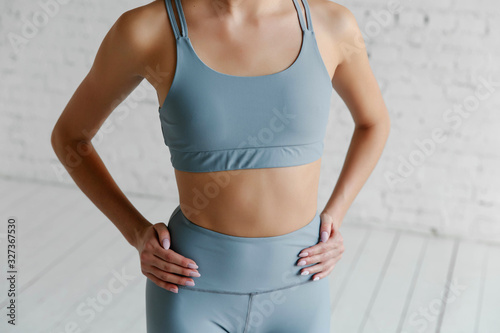 Close up image of middle eastern female in sports clothing relaxing after workout on grey background. Muscular female body with sweat. Image with copyspace for text
