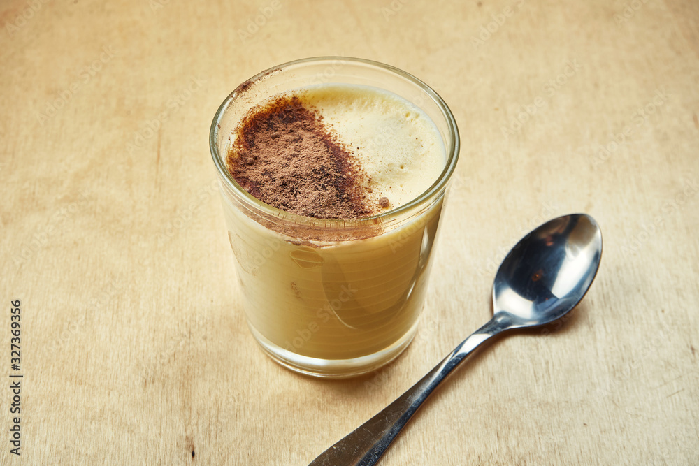 Close up view on tasty sweet tiramisu dessert in glass on wooden background. Italian cuisine dessert for coffee or tea. Close up view on tasty sweet tiramisu dessert in glass on wooden background. Italian cuisine dessert for coffee or tea.